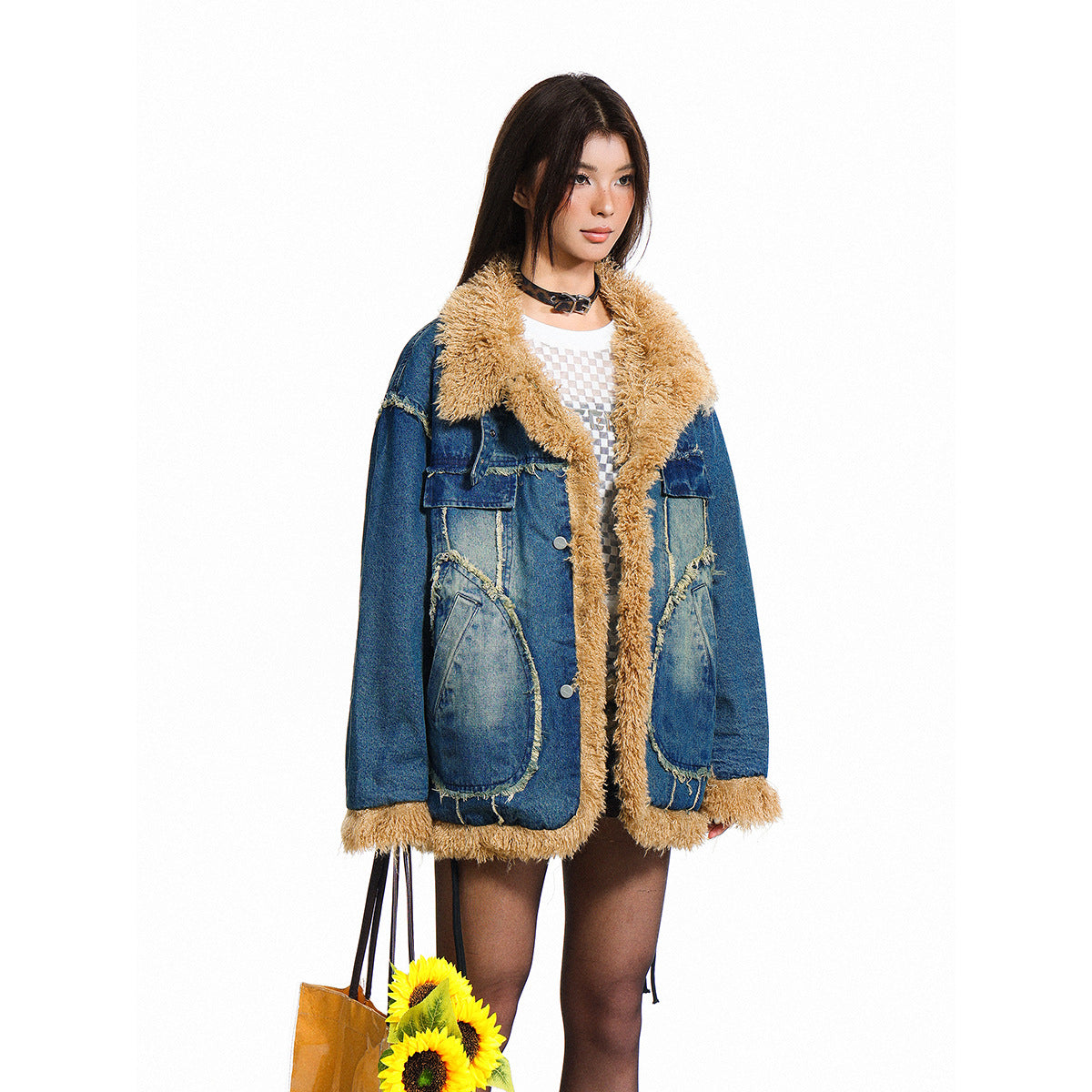 Model wearing an oversized blue denim jacket with tan shaggy trim, large patch pockets and button closure.