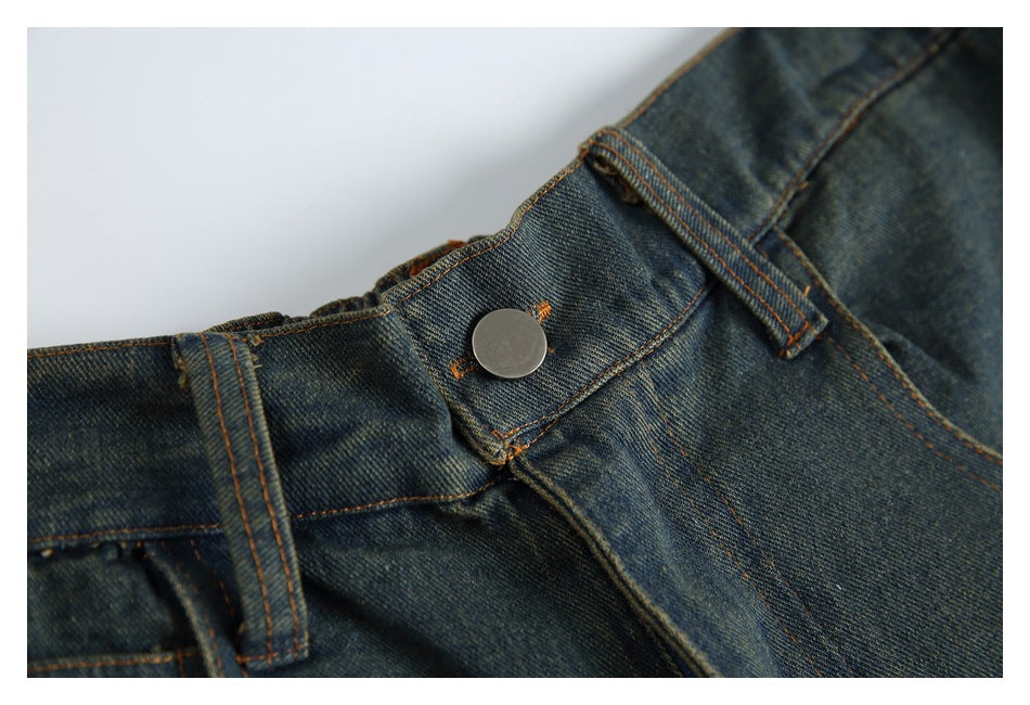 Close-up of the jeans' waistband, belt loop and plain metal button with orange stitching.
