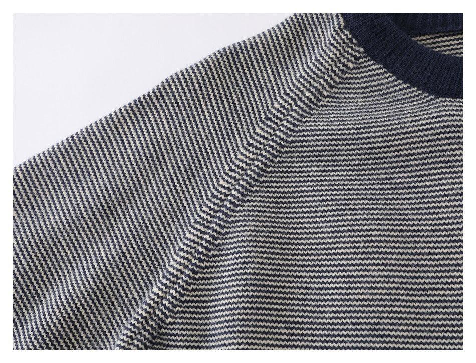 Close-up of the striped sweater shoulder and sleeve seam beside its navy ribbed neckline.