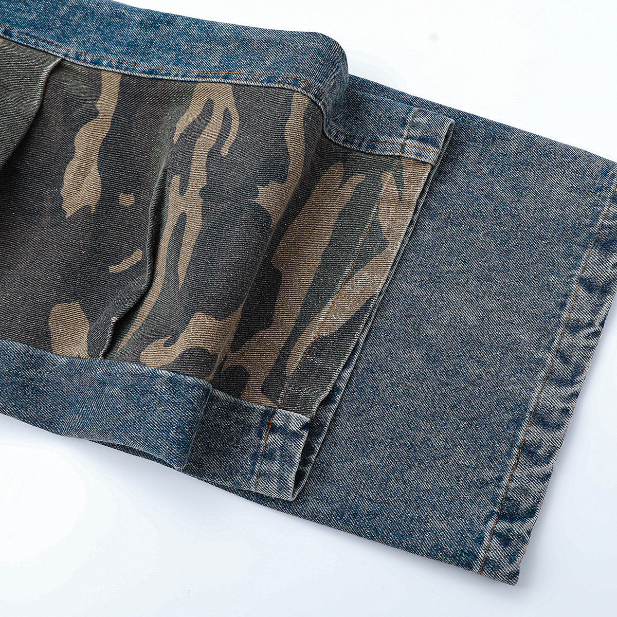 Close-up of a turned-up jeans leg revealing camouflage-patterned fabric inside the cuff.