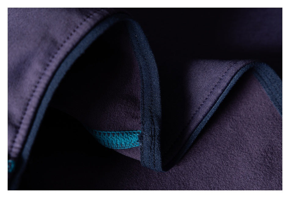 Close-up of folded dark purple garment fabric showing dark binding and teal overlock stitching.