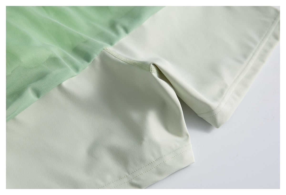 Close-up of pale mint garment fabric with a light green mesh panel and stitched hem.