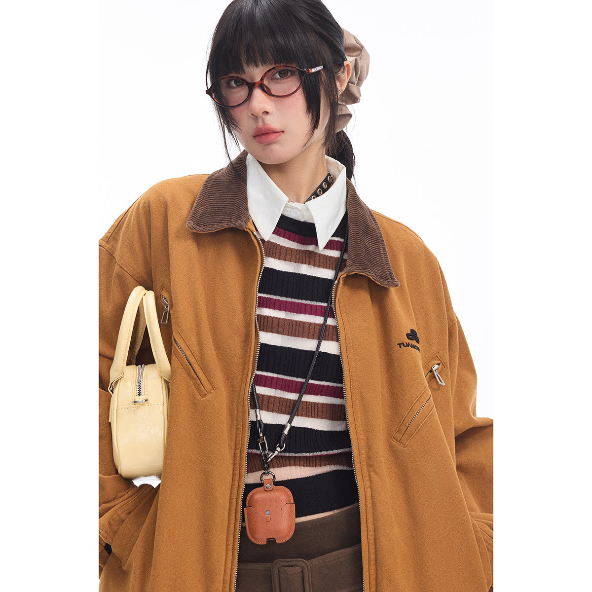 Close-up of a model wearing a mustard zip jacket with a brown corduroy-look collar and striped top.