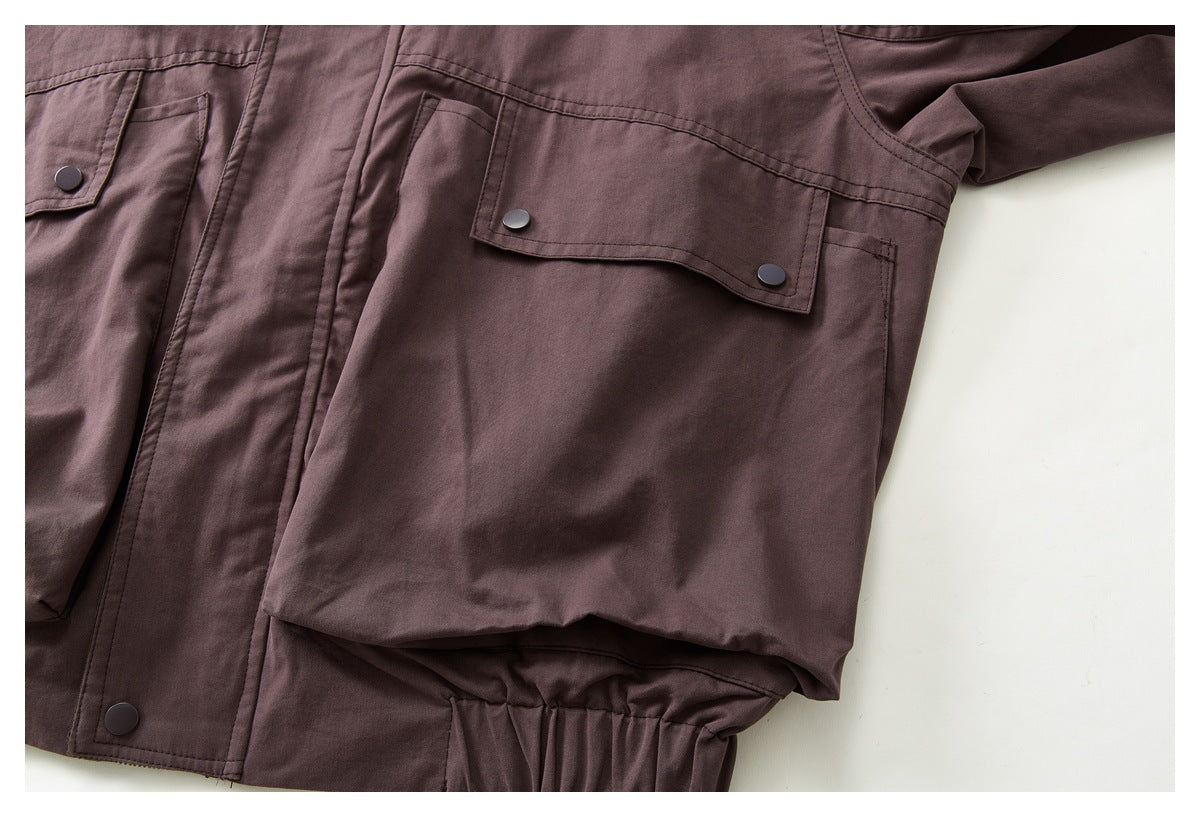 Close-up of a mauve-brown jacket front with snap-flap pockets, a snap placket, and a gathered hem.