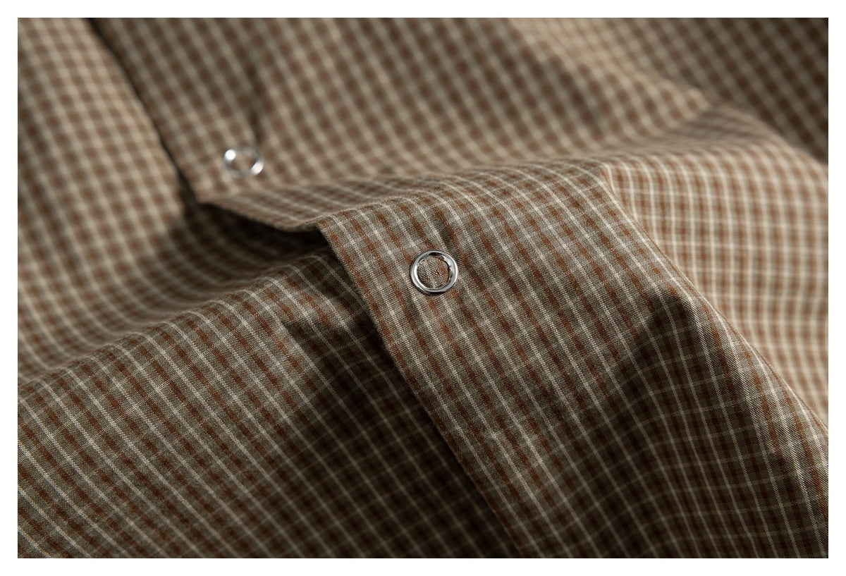 Close-up of a brown checked shirt with silver snap buttons on the front placket.