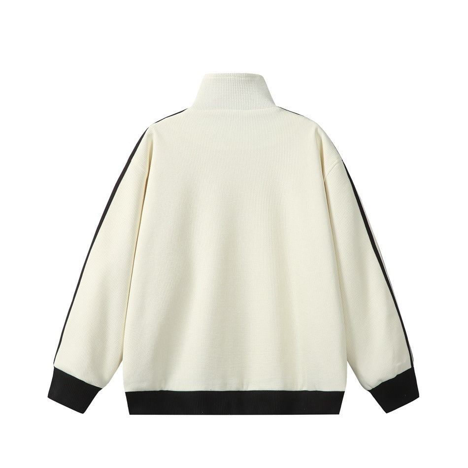 Back view of cream waffle-textured track jacket with stand collar, black ribbed hem and cuffs, and black sleeve stripes