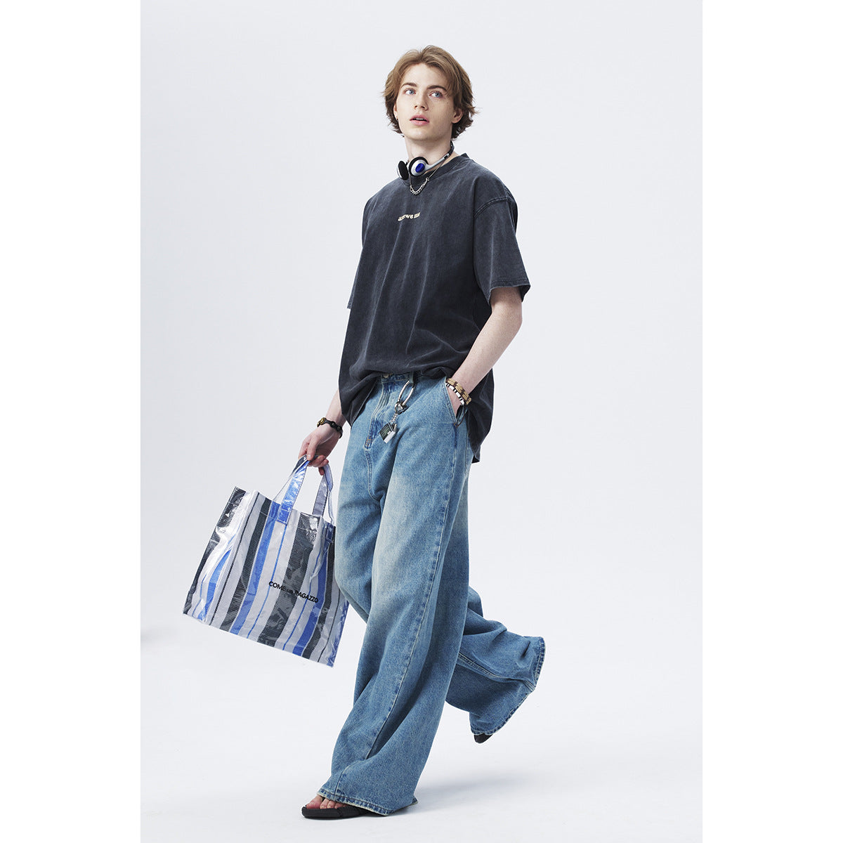 Model wearing an oversized dark washed T-shirt with small chest text and loose blue jeans.