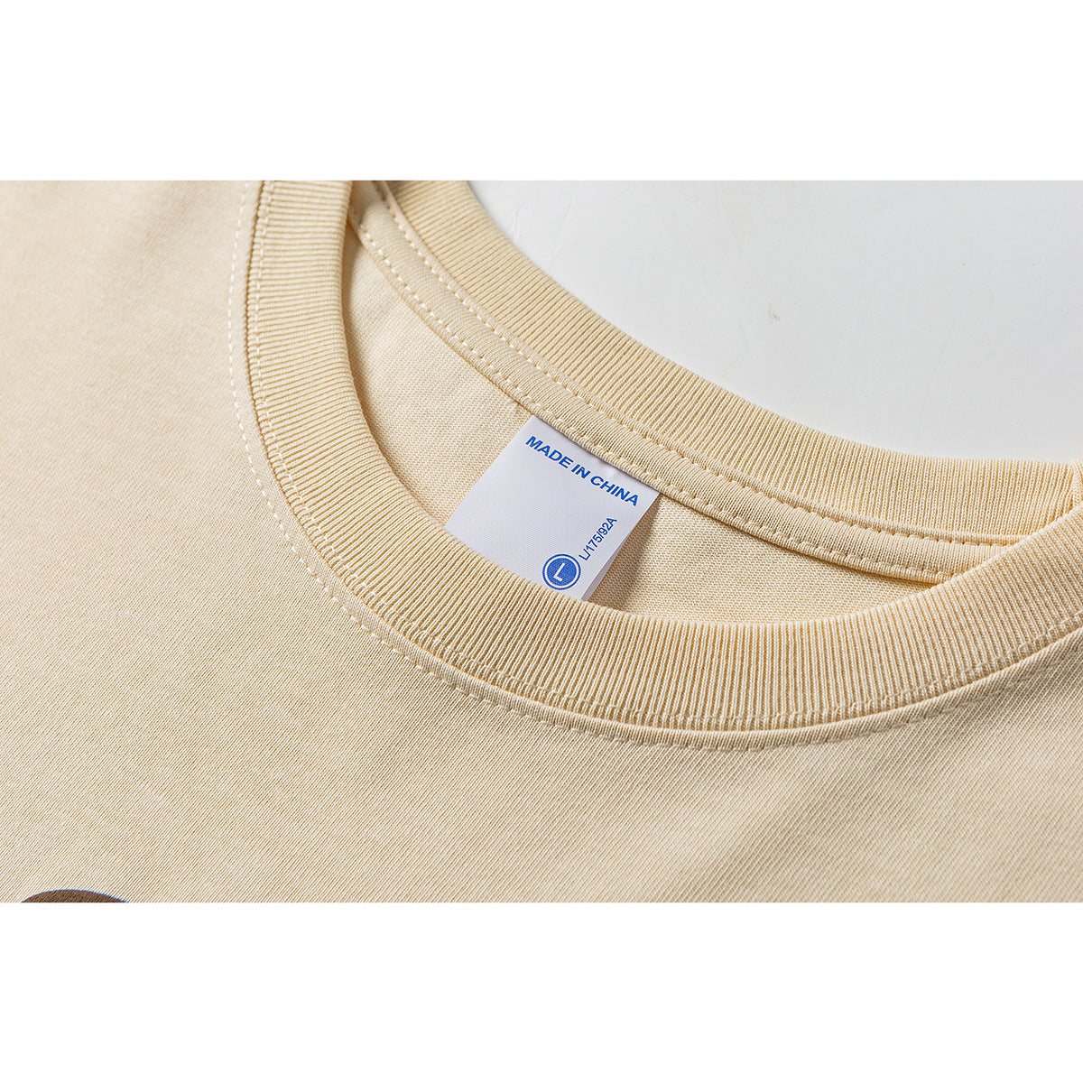 Close-up of a pale yellow T-shirt collar and a sewn label reading “Made in China” and size L.