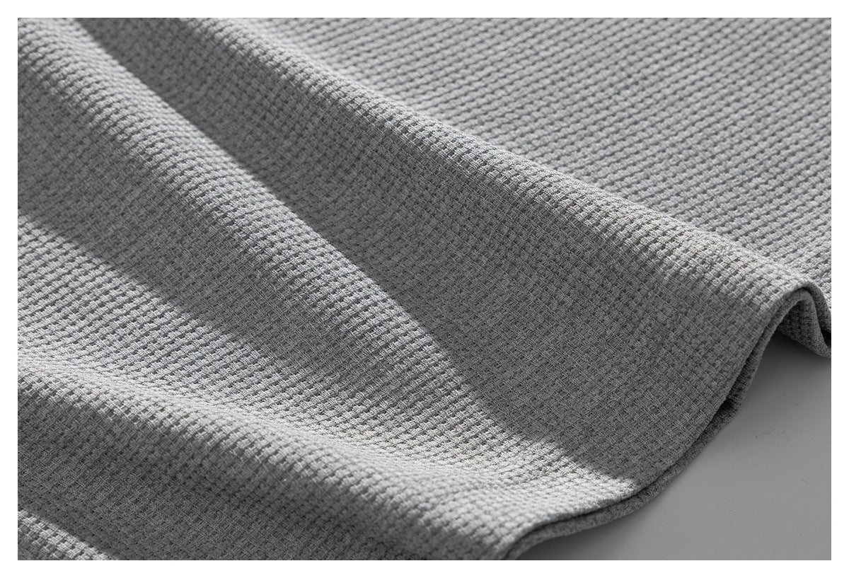 Close-up of light gray textured shirt fabric draped in folds.
