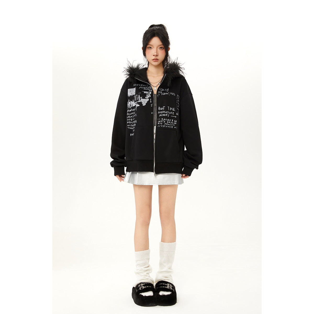 Model wearing a black oversized zip hoodie with fur-trimmed hood and gray text print, paired with a silver skirt.
