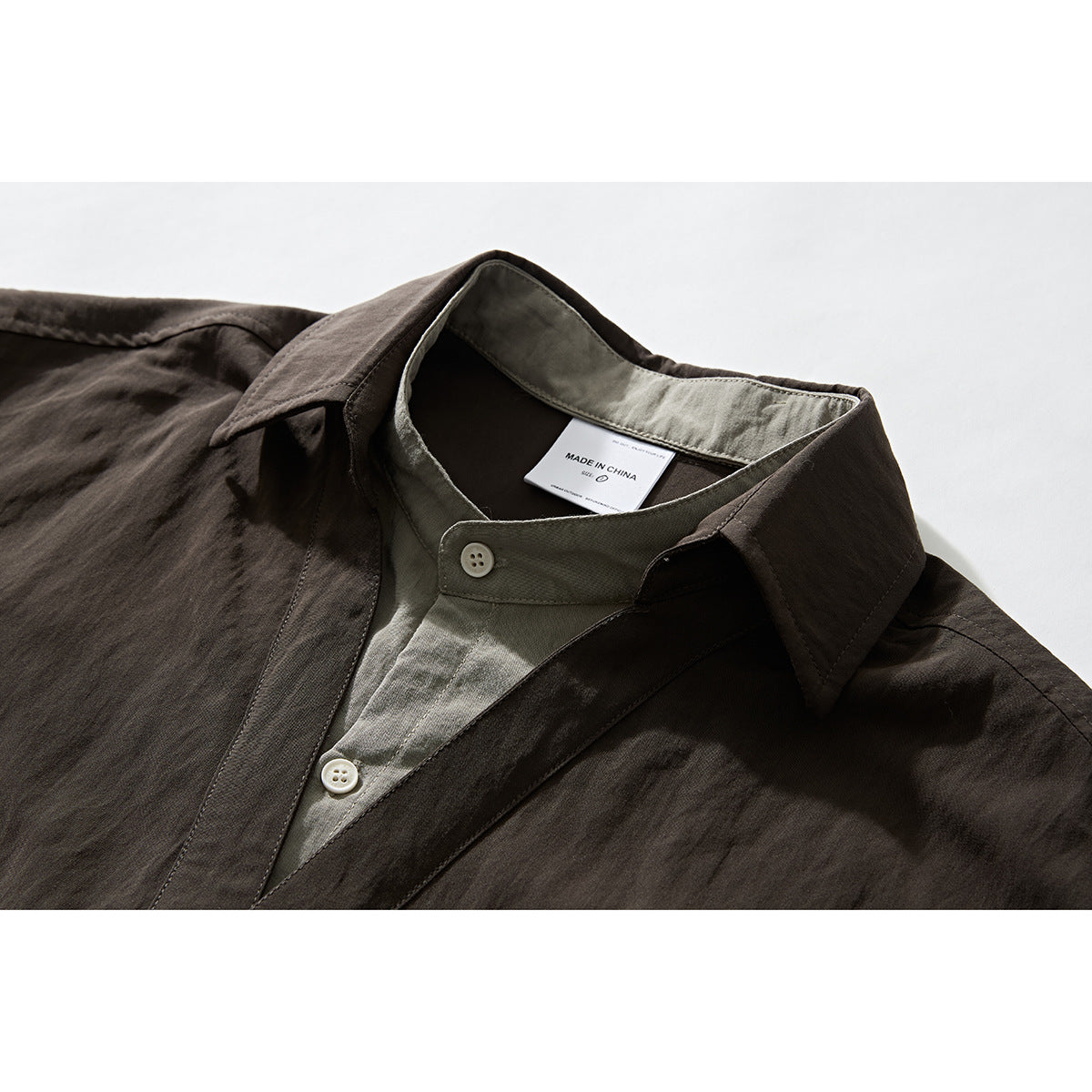 Close-up of a dark brown button-up shirt collar with contrasting olive inner facing and white buttons.