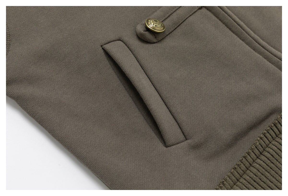 Close-up of a slanted welt pocket and decorative brass button on the taupe jacket.