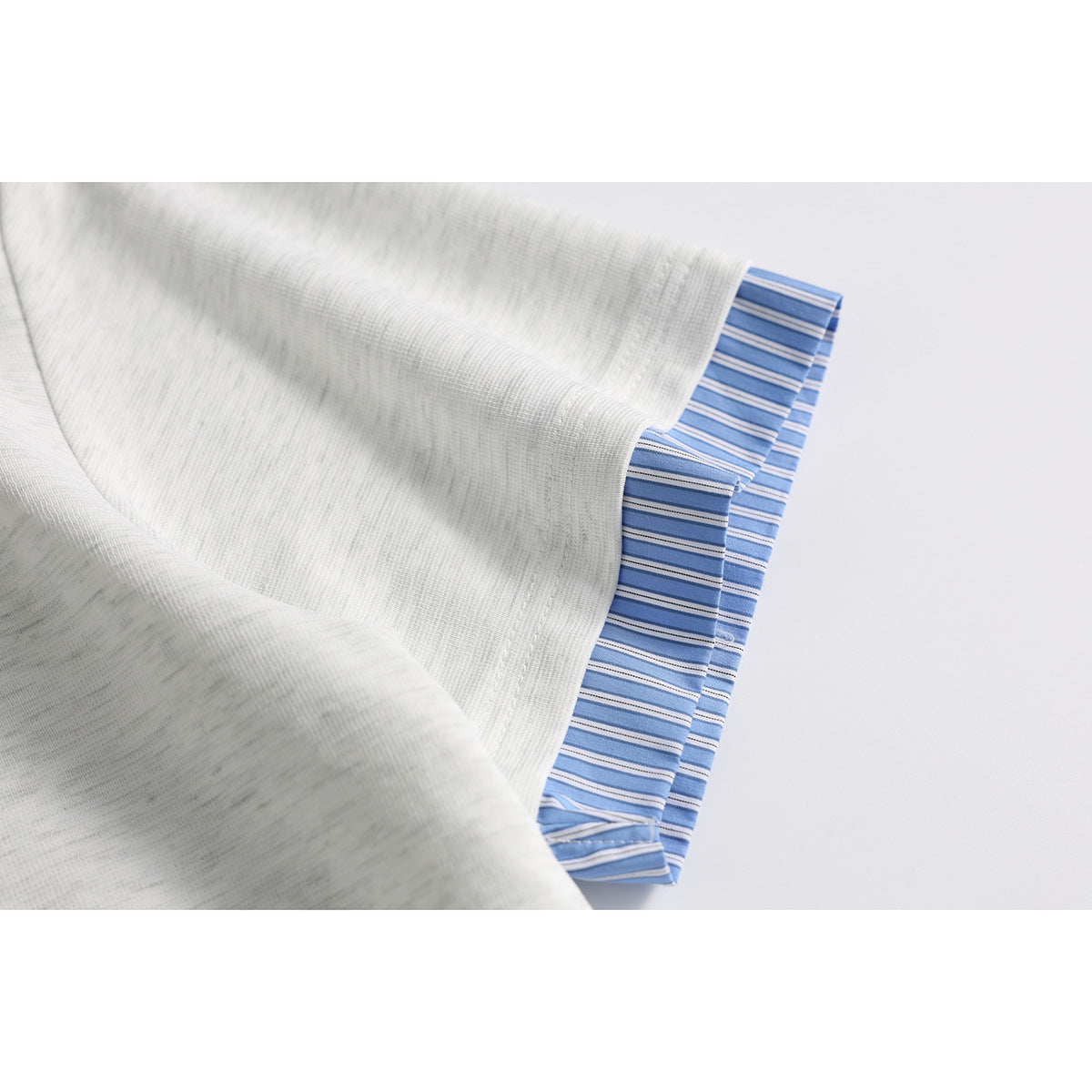 Close-up of an off-white short sleeve with a blue striped cuff lining.