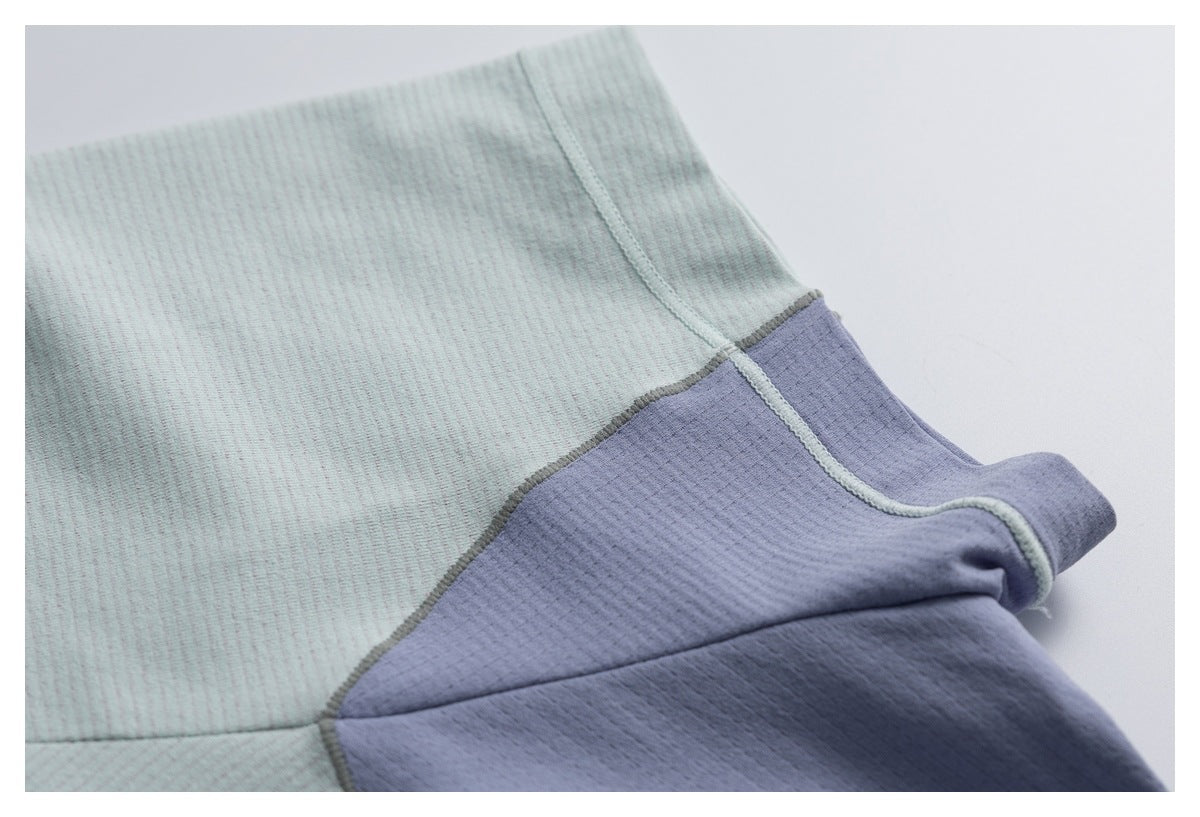Close-up of pale gray-green and lavender fabric panels meeting at a curved stitched seam.