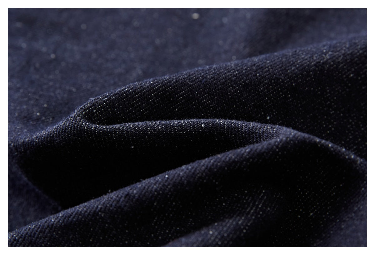 Macro view of dark indigo denim fabric gathered into soft folds.