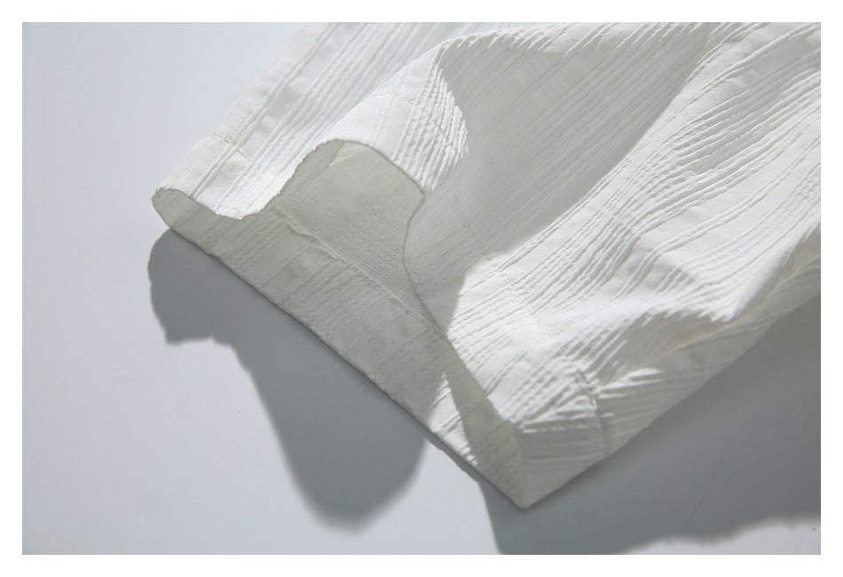 Close-up of a white shirt sleeve cuff and its textured fabric.