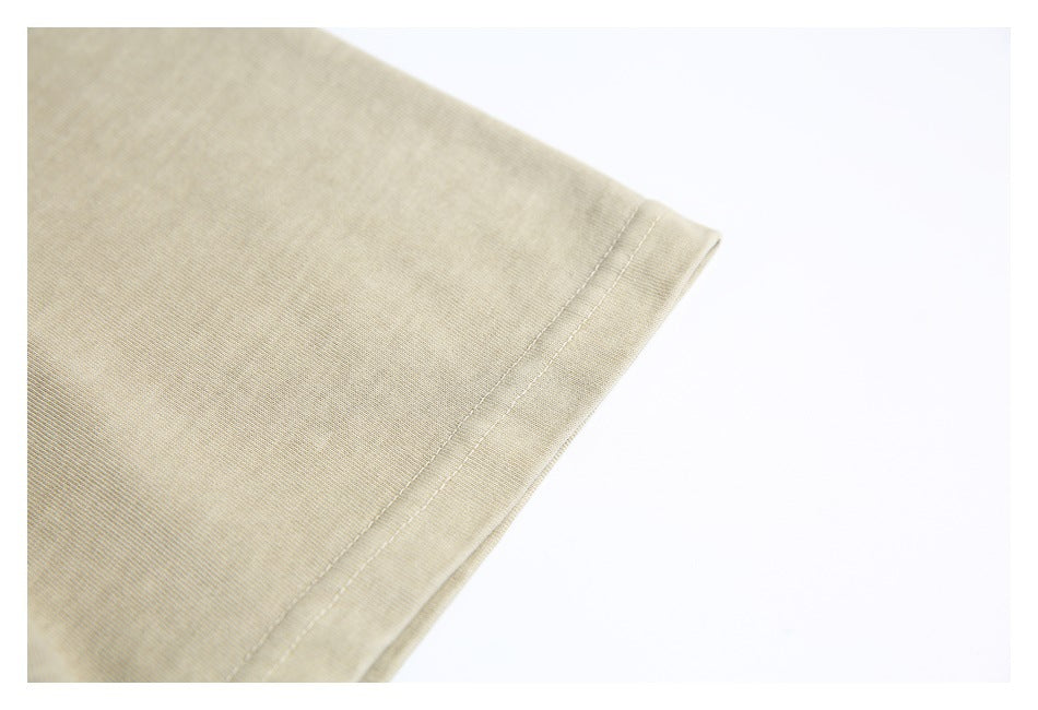Close-up of the sleeve hem and stitching on a sand-beige T-shirt.