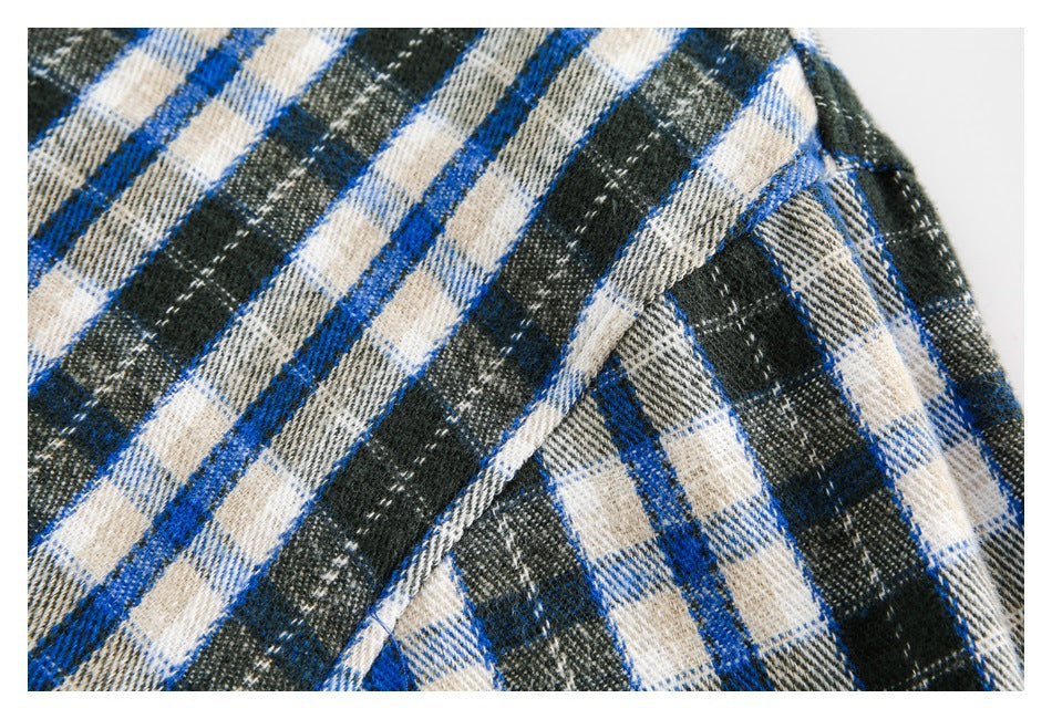 Close-up showing a seam and overlapping panels of blue, black, and cream plaid fabric.