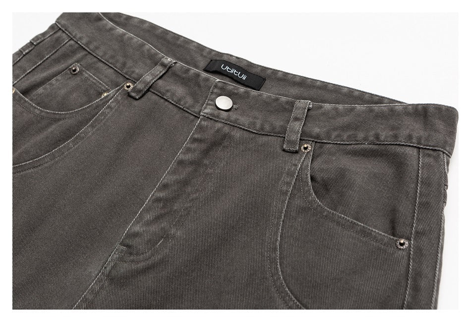 Close-up of the front waistband of charcoal-gray jeans with button closure, belt loops, pockets, and a sewn-in label.