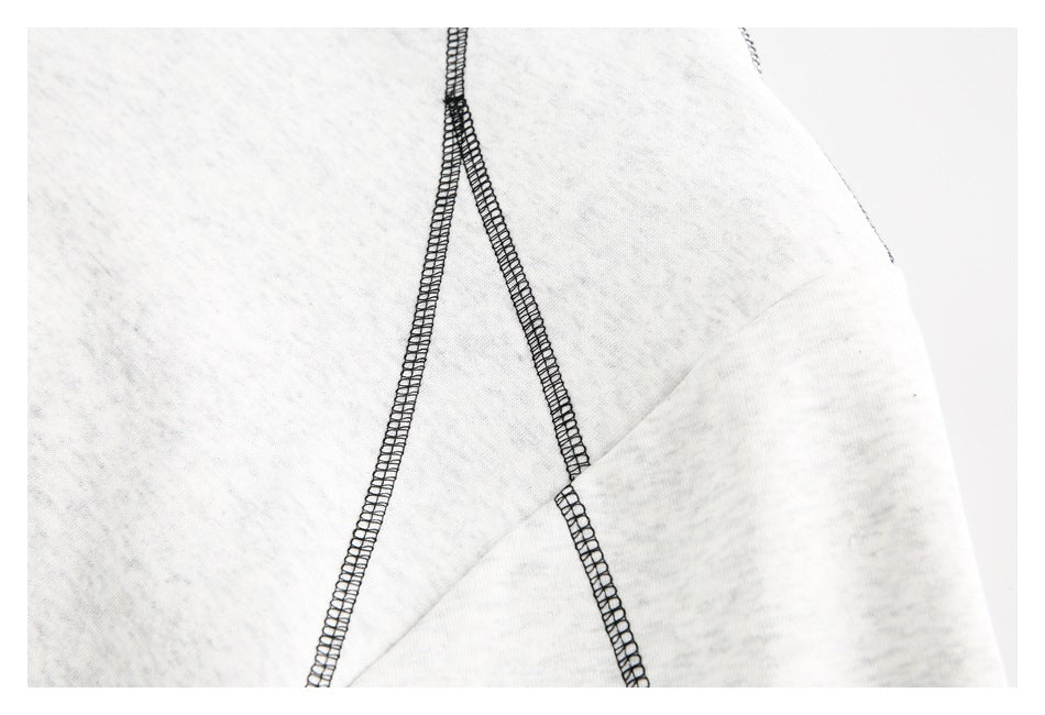 Close-up of black overlock seams crossing the off-white sweatshirt fabric.