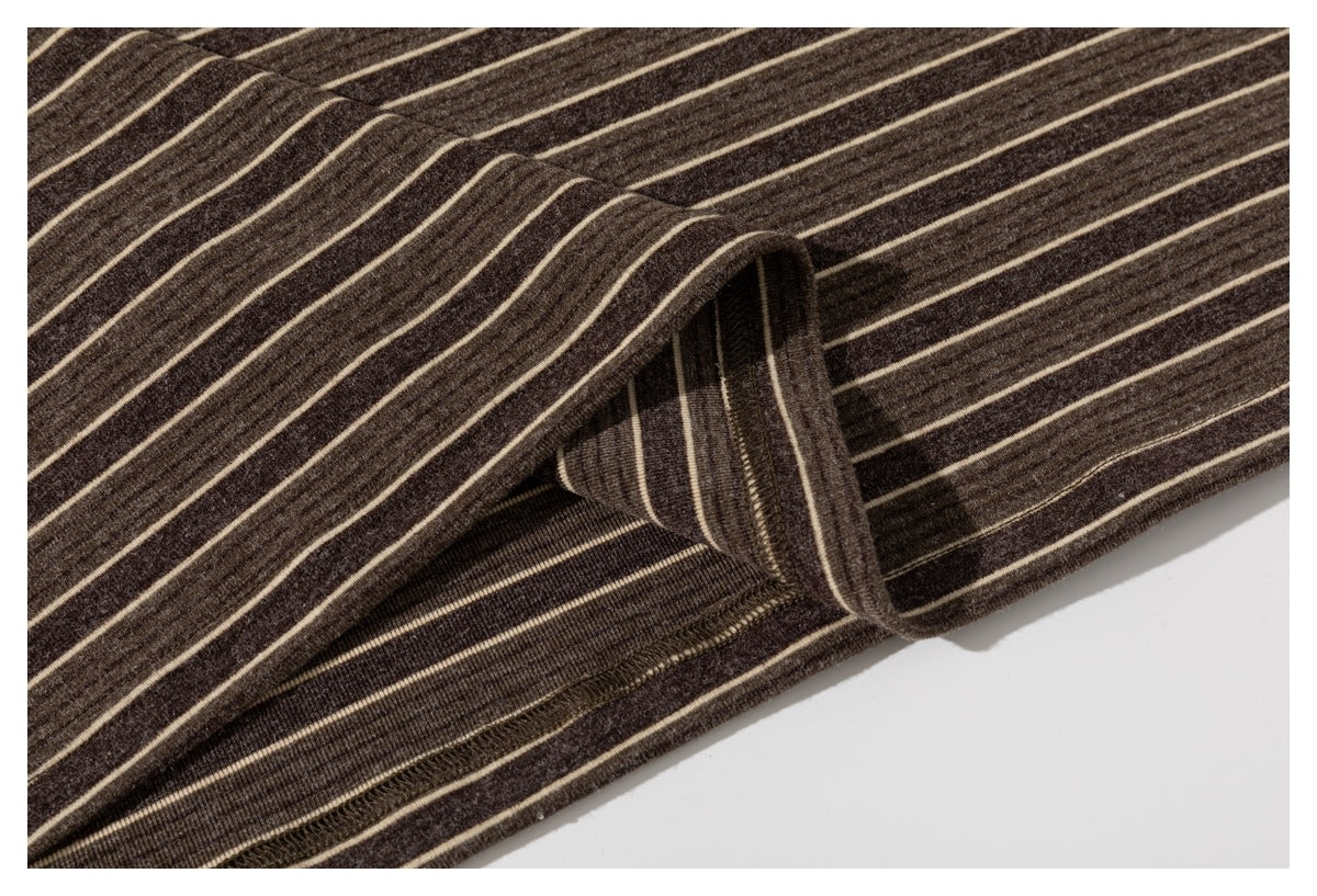 Close-up of a striped shirt's folded seam and stitching on dark brown fabric.
