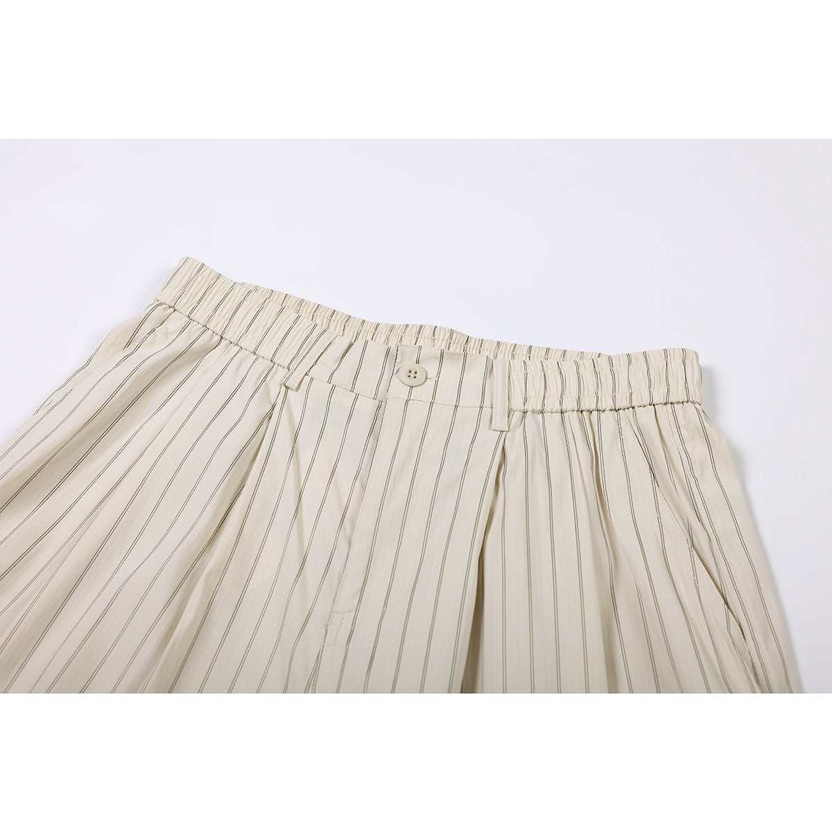 Close-up of cream pinstriped shorts showing the elastic waistband, button closure, belt loops, and front pleats.