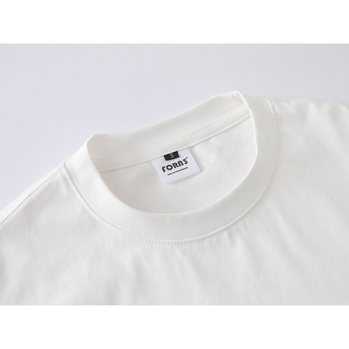 Close-up of a white T-shirt's ribbed crew neck and sewn neck label.