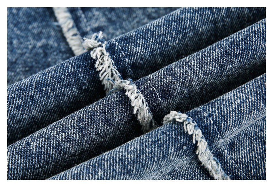 Close-up of dark blue denim with prominent white frayed seams and diagonal twill texture.