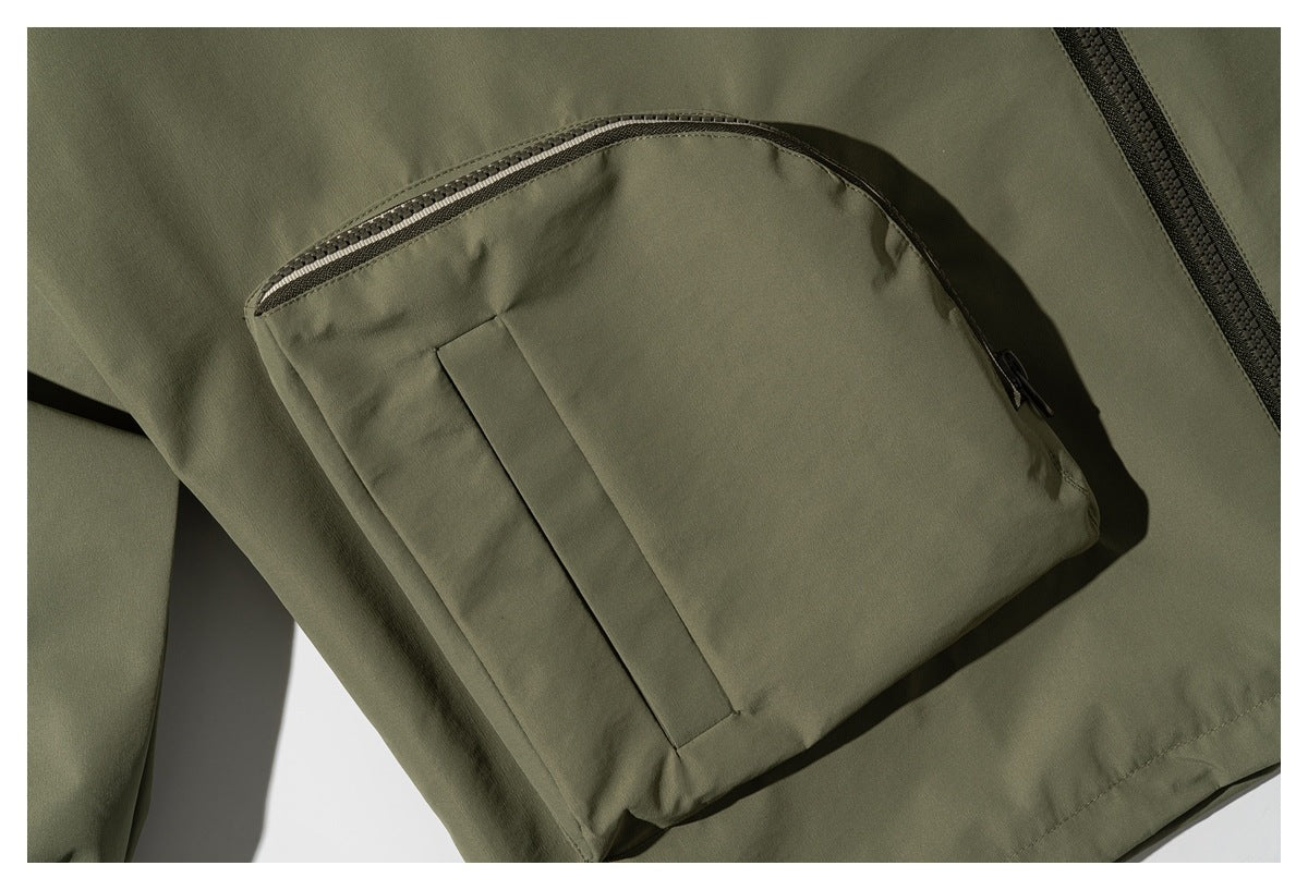Close-up of an olive jacket pocket with a curved zipper and vertical seam detail.