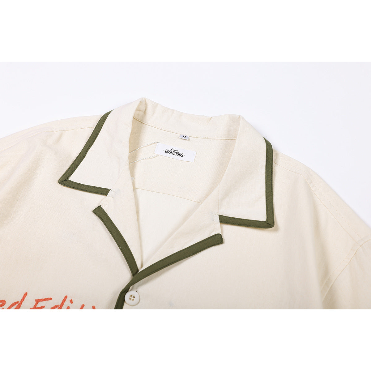 Close-up of an ivory shirt collar with olive-green piping, a white button, and a visible neck label.