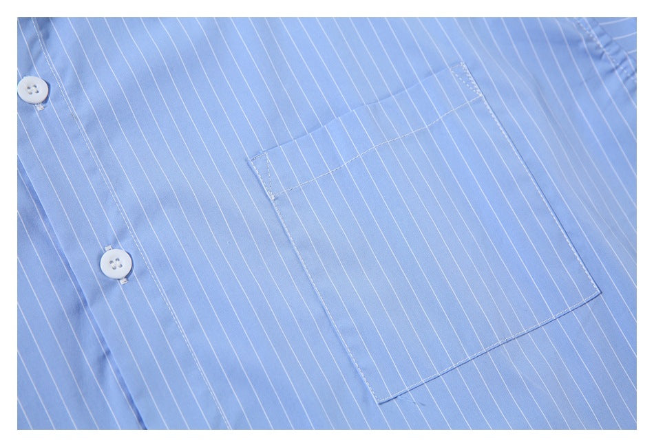 Close-up of the button placket and square chest pocket on a light blue pinstriped shirt.