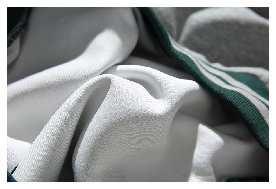 Close-up of the light-colored inner side of a gray sweatshirt beside its striped dark green trim.
