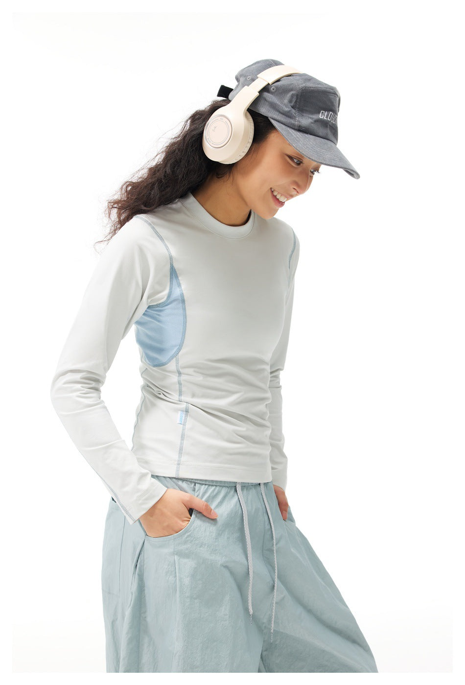 Model wearing a white long-sleeve top with pale blue side panels and light blue pants, shown in a three-quarter view.