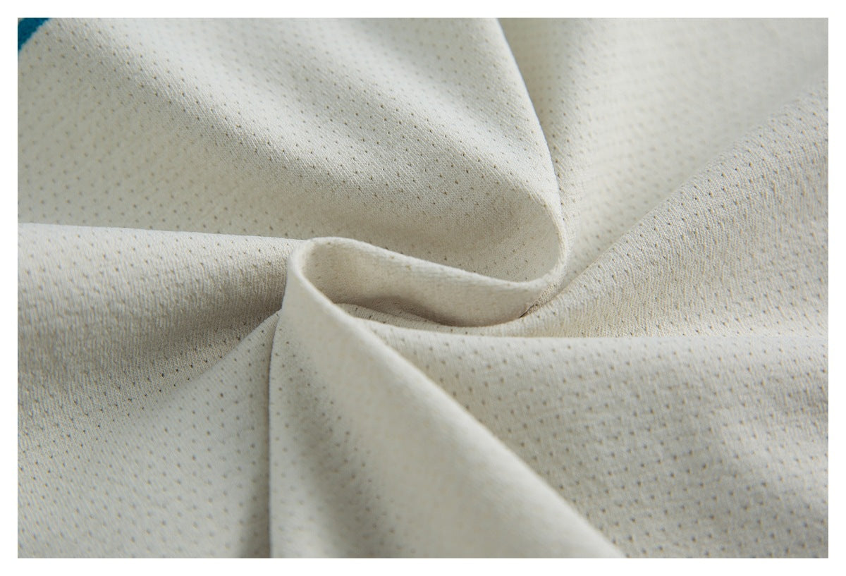 Close-up of ivory perforated fabric arranged in soft folds, showing its textured surface.