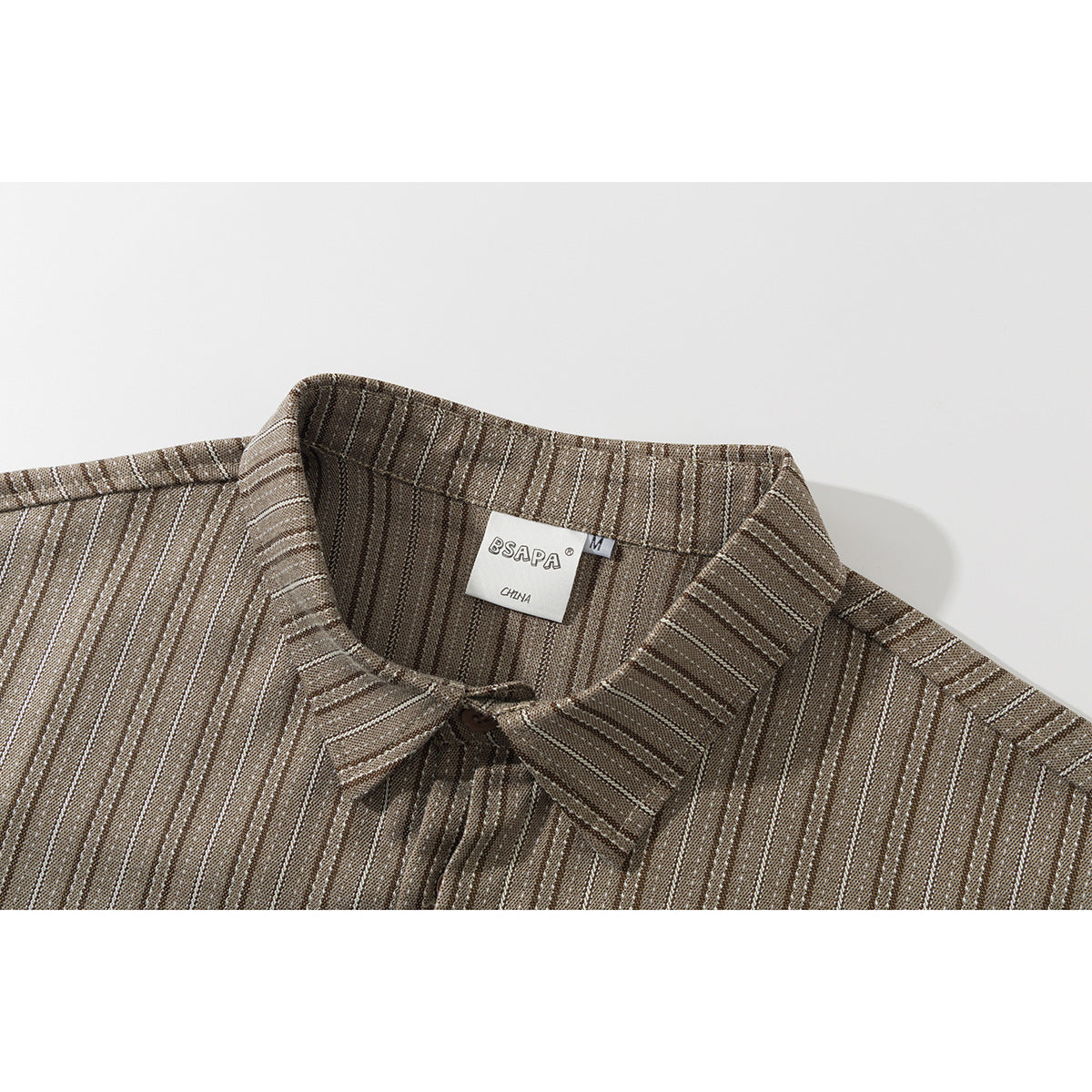Close-up of a brown striped shirt collar with a sewn neck label.