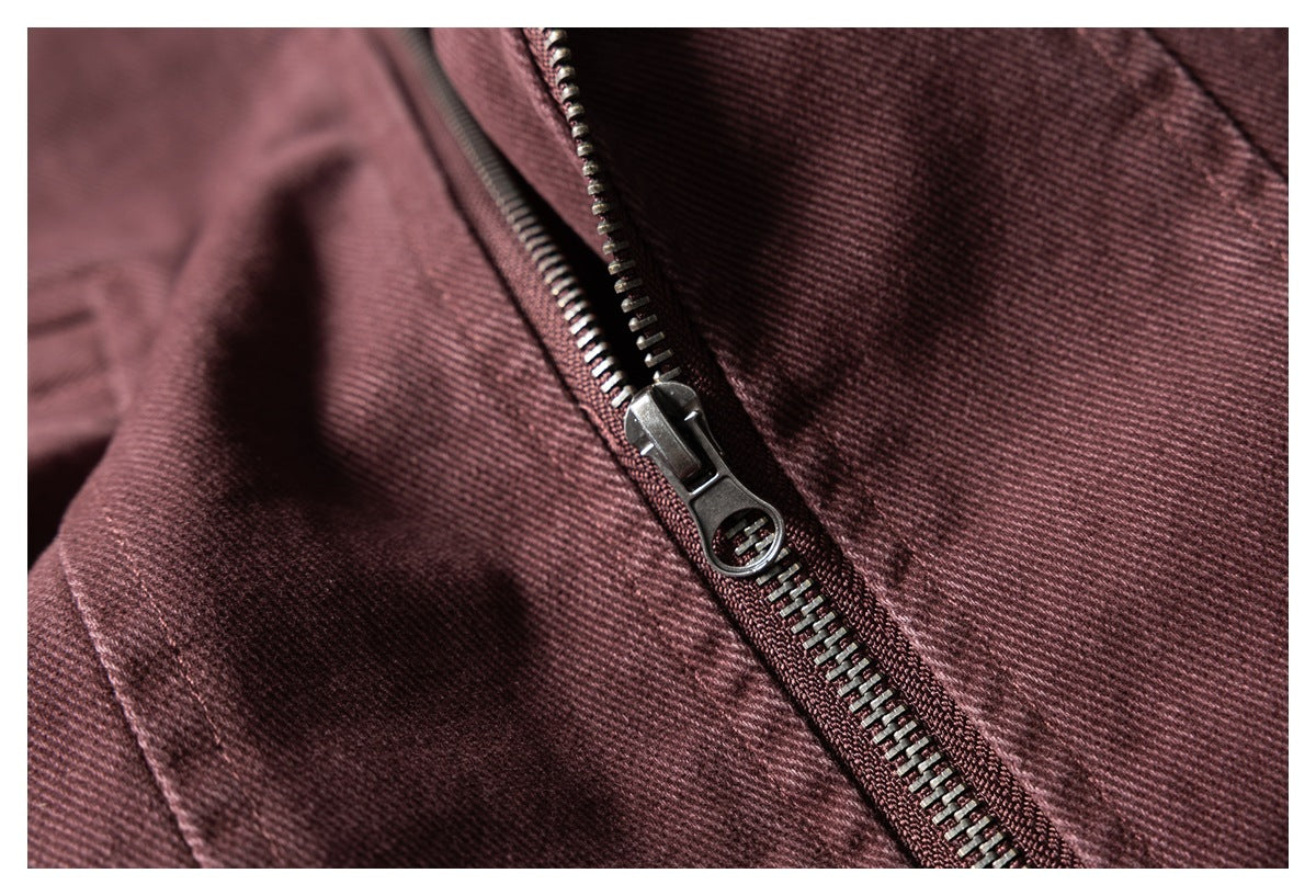 Close-up of a dark metal zipper and pull on burgundy fabric.