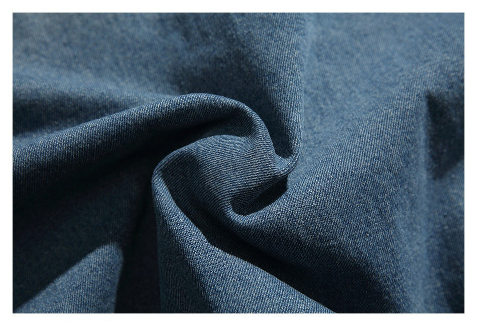Close-up of blue denim fabric folded to show its texture and drape.