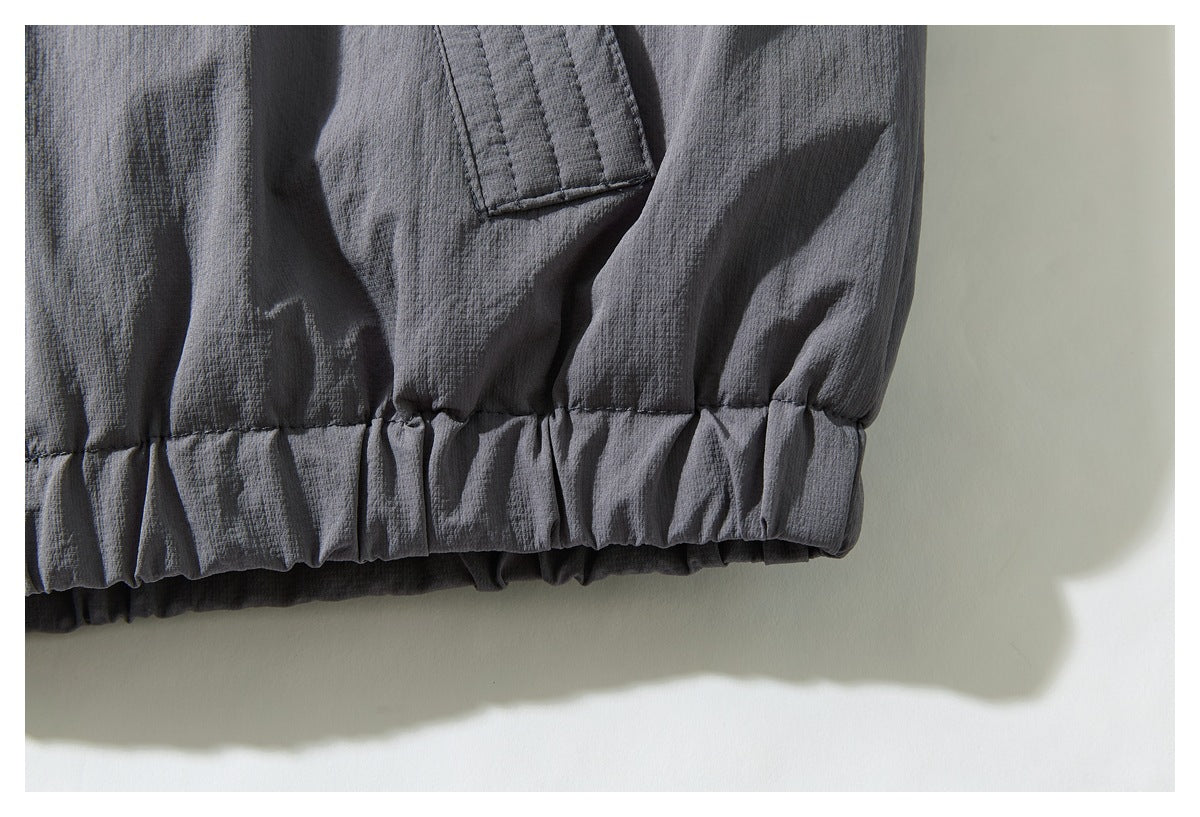 Close-up of a dark gray garment's gathered elastic hem and stitched fabric tab.