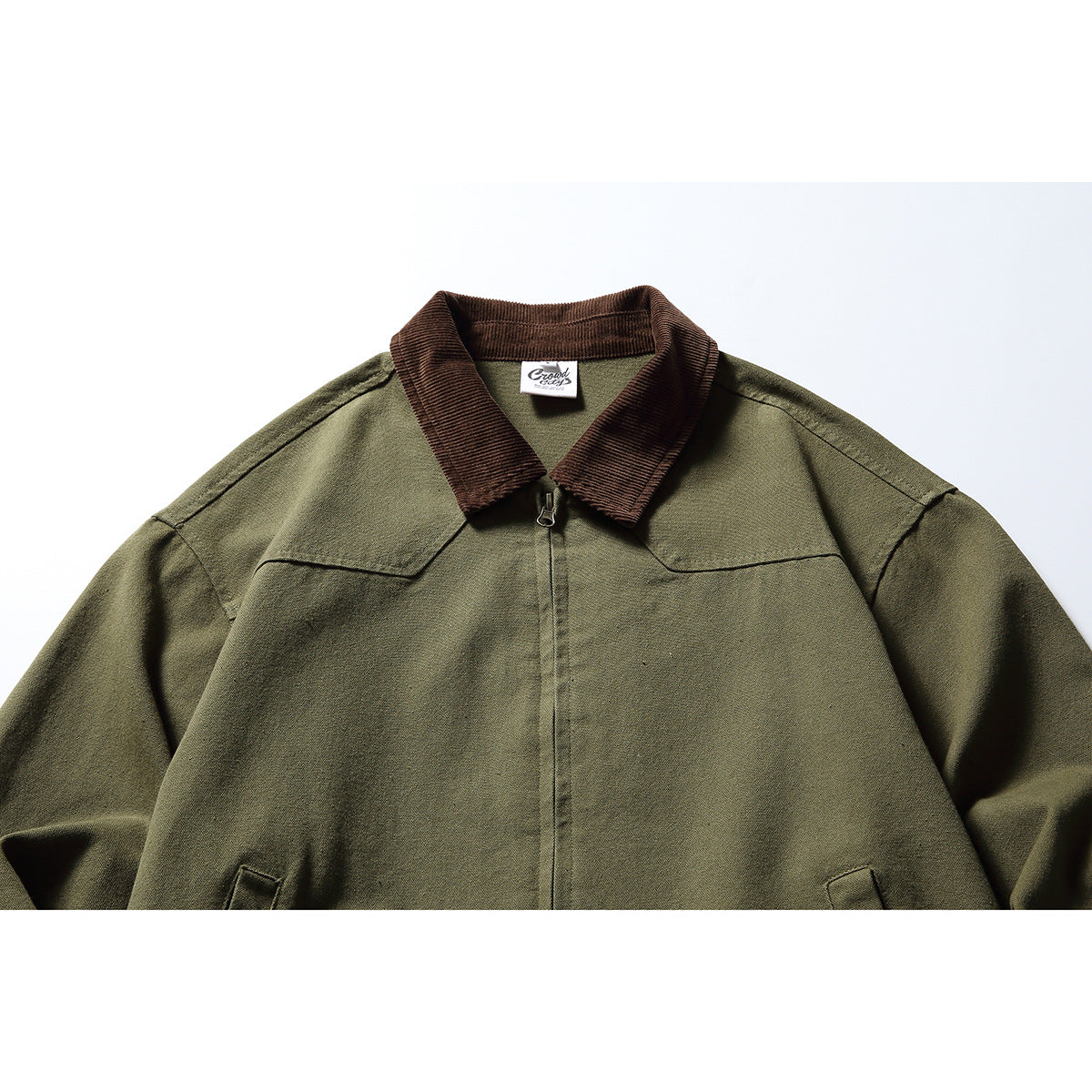 Close view of an olive zip jacket with a brown ribbed collar and shoulder seams.