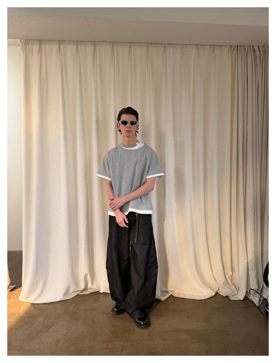 Front view of a model wearing an oversized gray T-shirt with white contrast trim and a visible white underlayer.