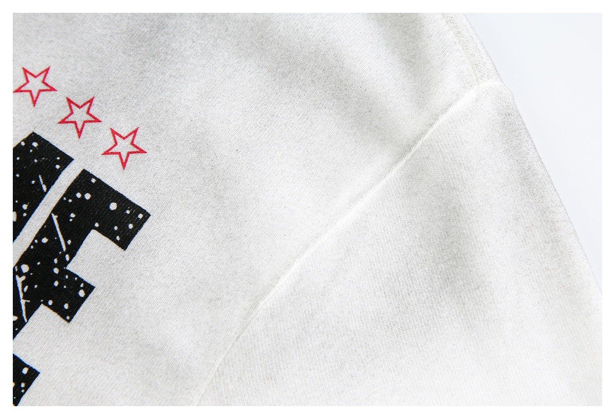 Close-up of the sleeve seam and shoulder on a white T-shirt, with part of its black-and-red print visible.