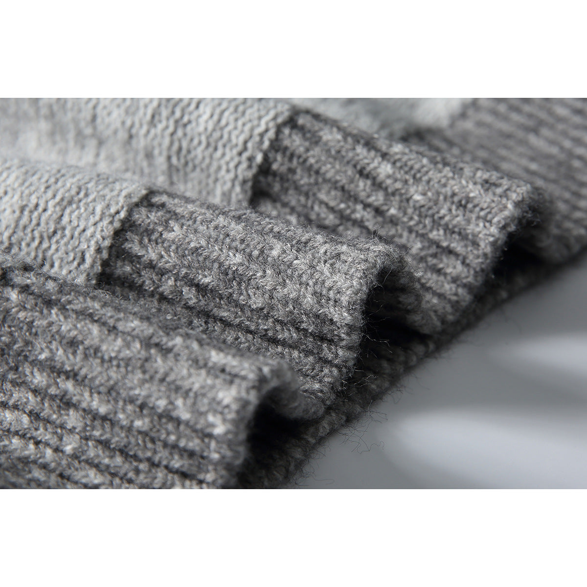Macro view of the textured gray knit and raised cable pattern on a sweater.