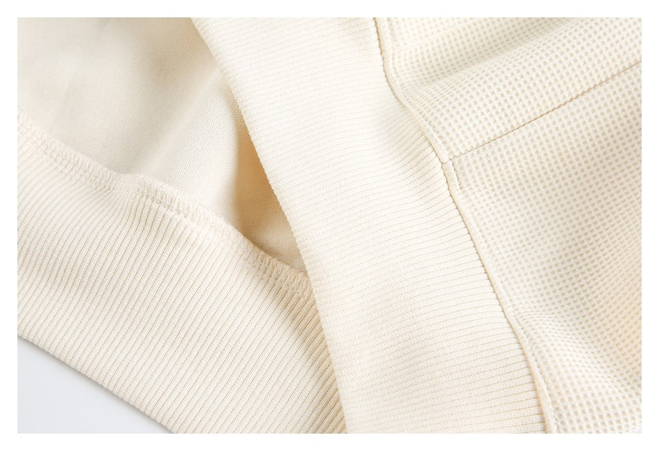 Close-up of an ivory textured shirt showing ribbed trim, seams, and a small-grid weave.