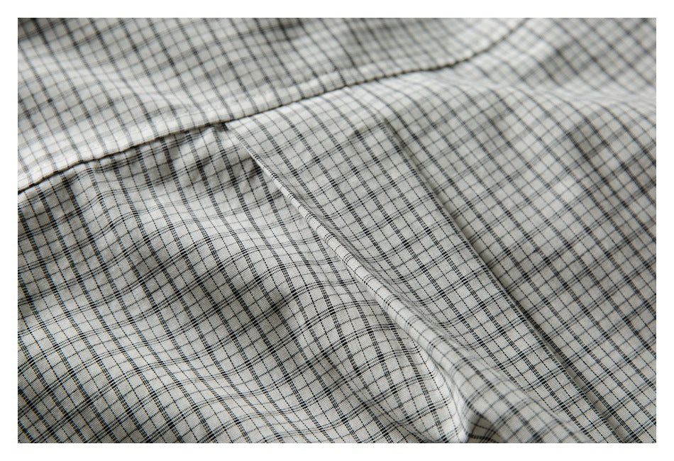 Close-up of off-white black-and-gray plaid fabric, showing a folded edge and stitching.