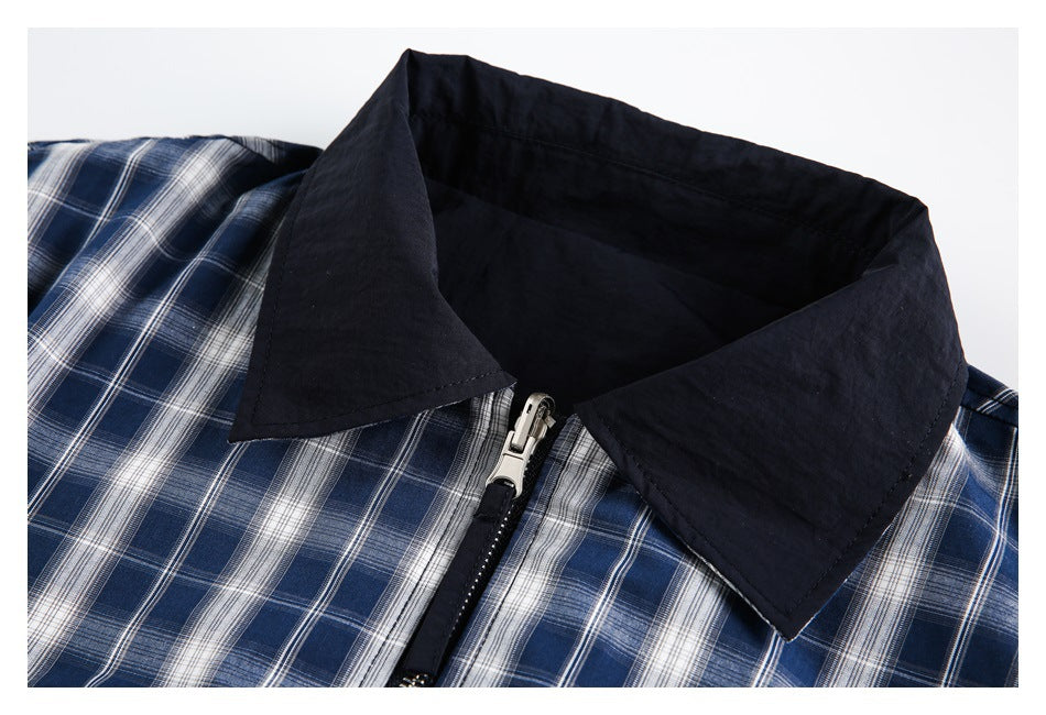Close-up of the jacket's dark pointed collar and zipper over blue-and-white plaid fabric.