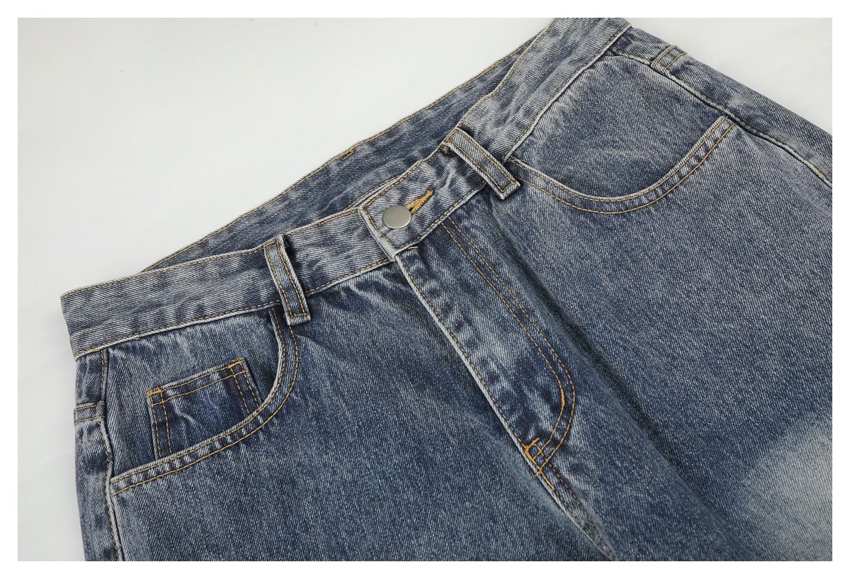 Close-up of the front waistband, button, fly and pockets on blue acid-wash jeans.