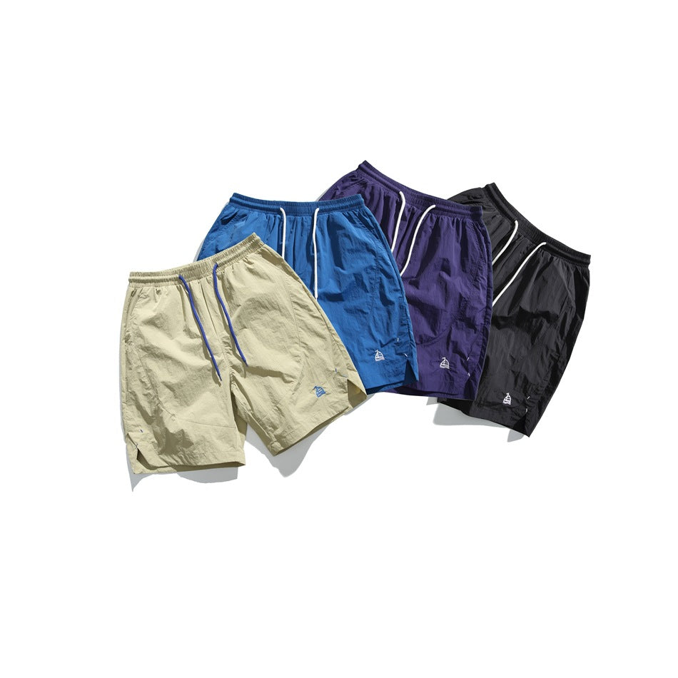 Four pairs of shorts shown together in beige, blue, purple, and black, with elastic waists and drawstrings.