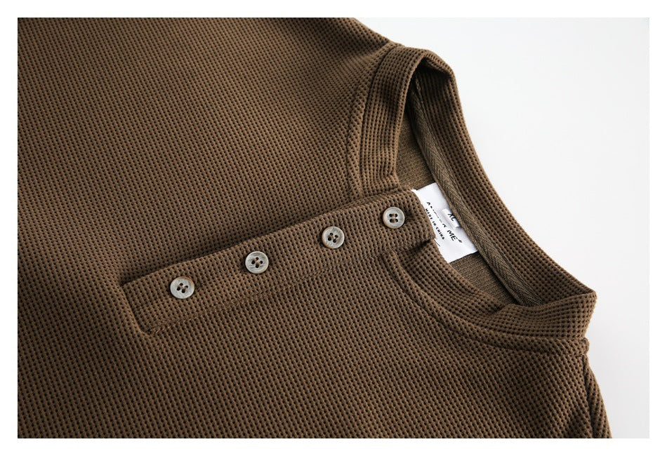 Close-up of a brown waffle-knit top showing its buttoned placket, collar and small inner neck label.
