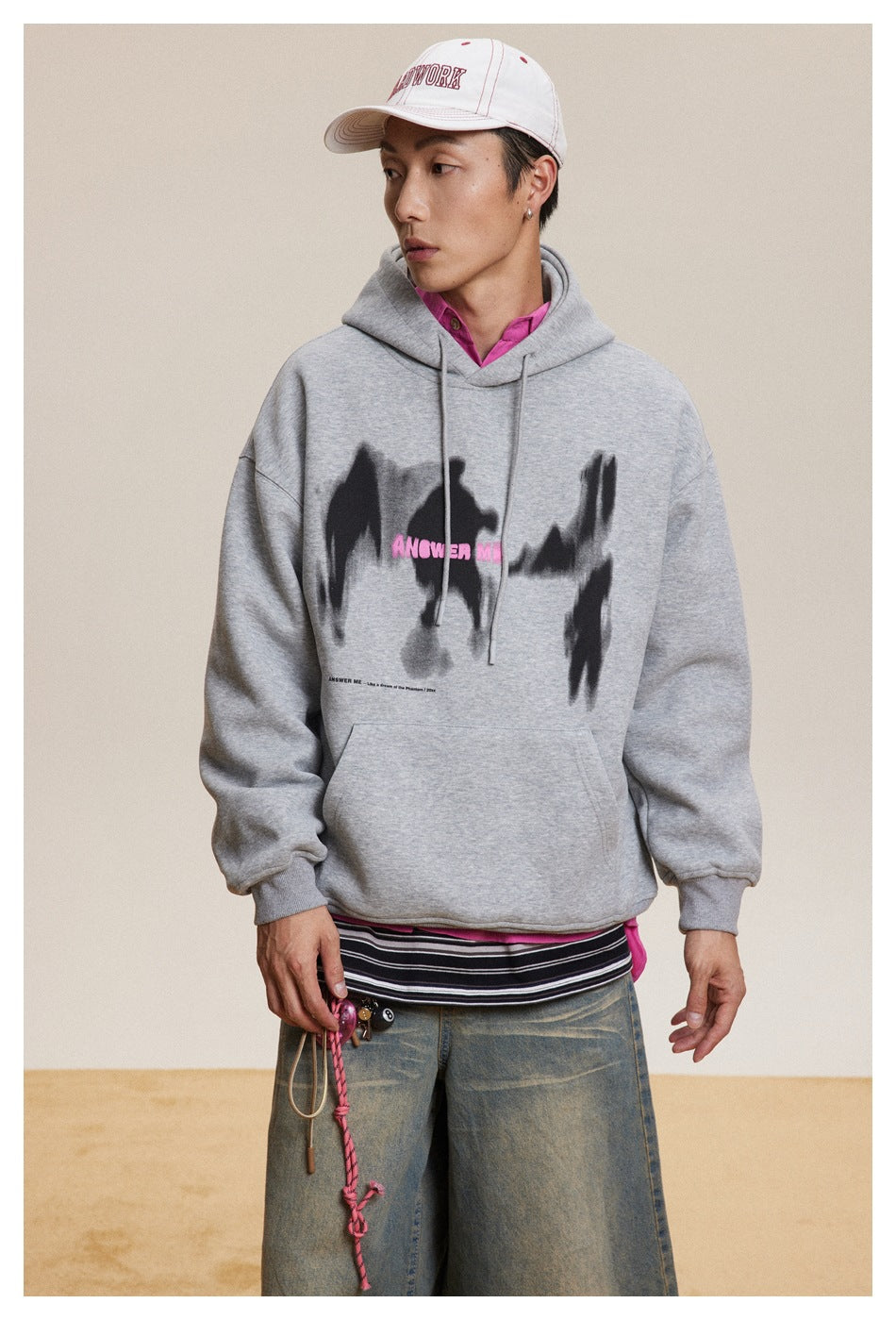 Model wearing a gray hoodie with a black-and-pink chest graphic, shown from the front.