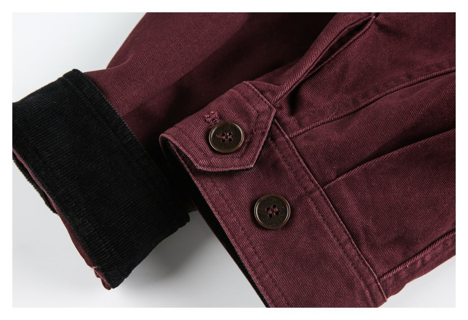 Close-up of a burgundy jacket sleeve with two buttons and a black ribbed cuff.